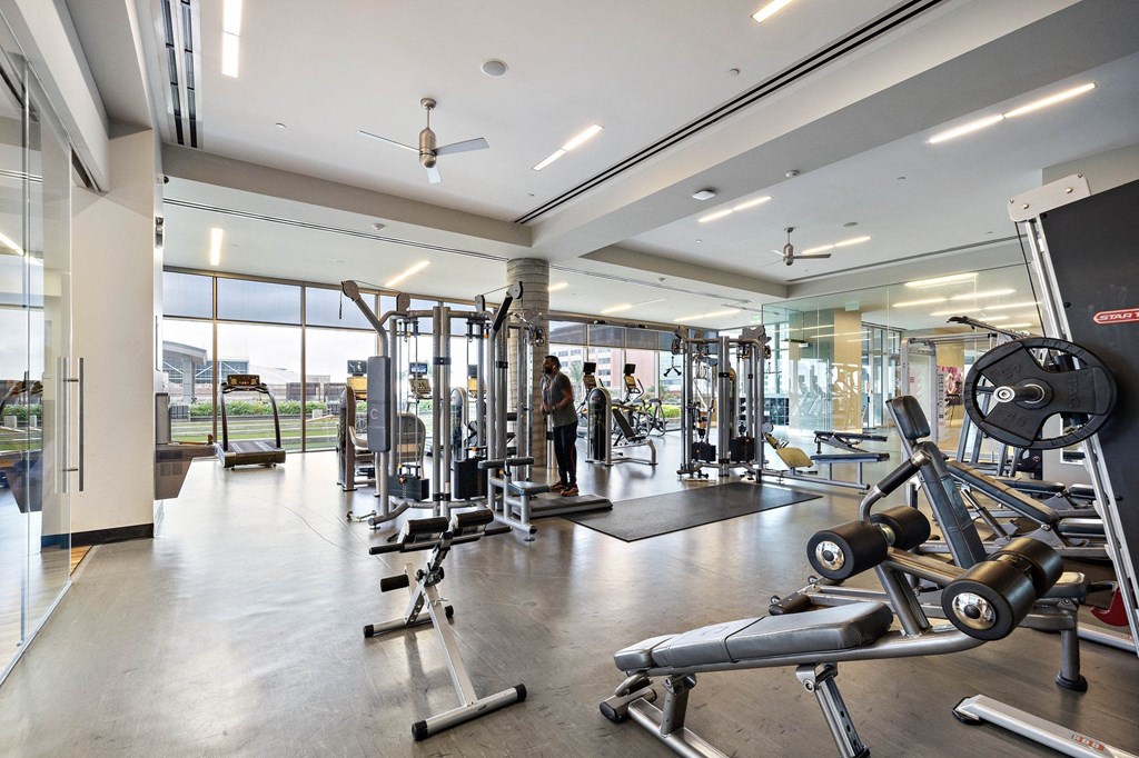 a gym with weights and other exercise equipment in a building with large windows