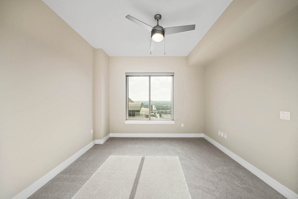 an empty living room with a ceiling fan and a window