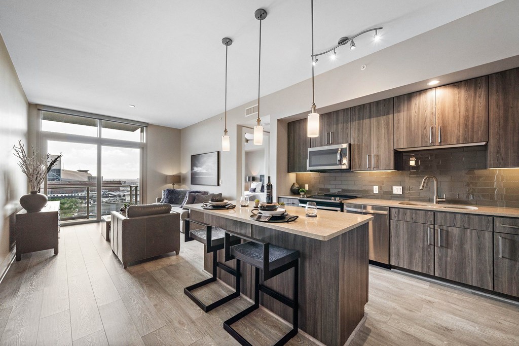 an open kitchen and living room with a large island with chairs