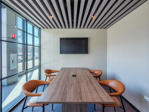 a conference room with a wooden table and chairs and a television