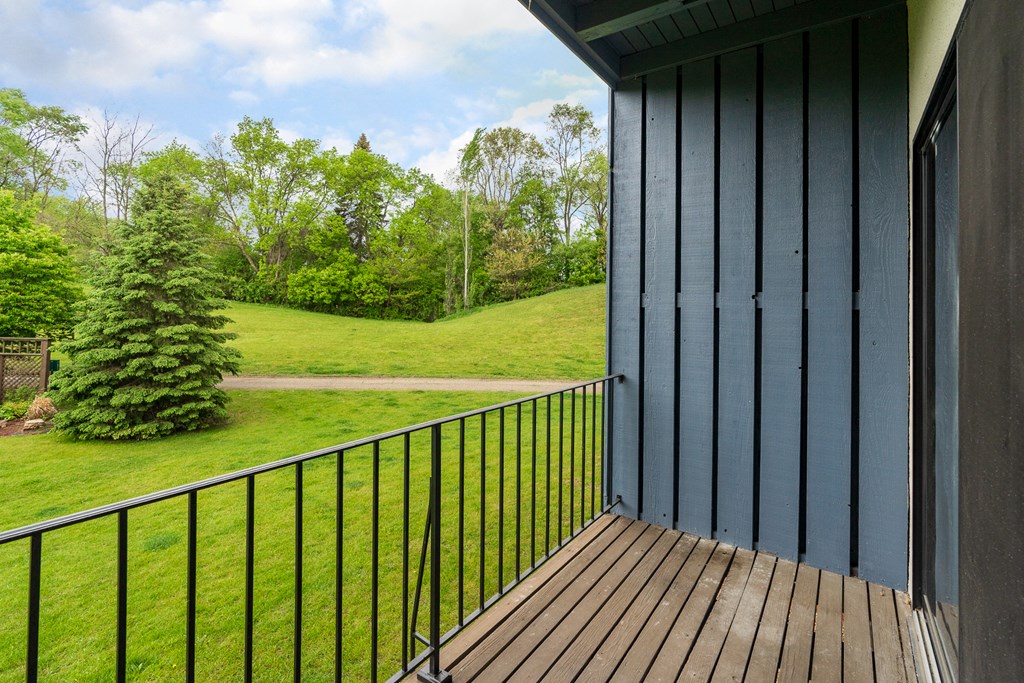 a balcony with a view of a yard and trees