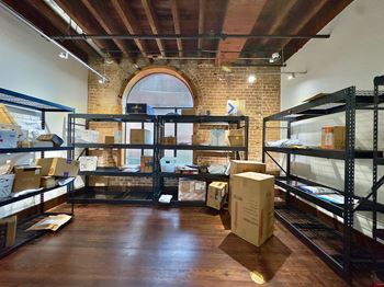 A warehouse with boxes on the floor and shelves.