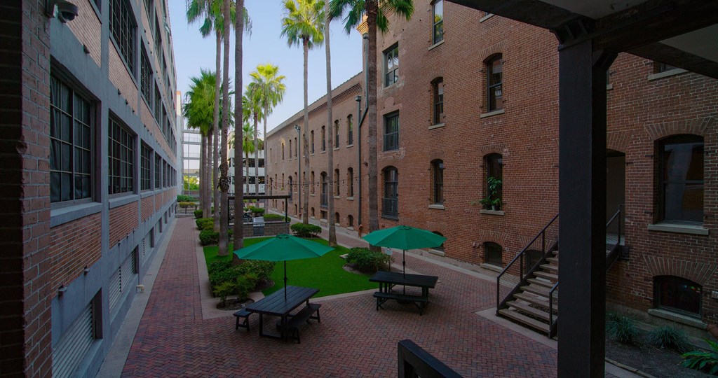 A courtyard with a green umbrella and benches.