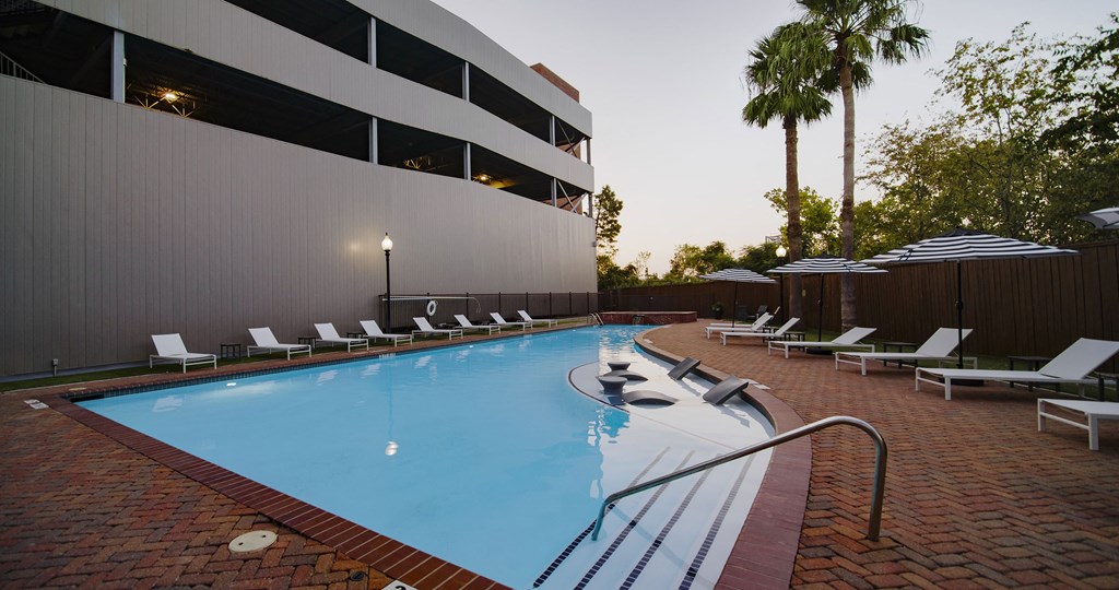 A swimming pool surrounded by lounge chairs and umbrellas.