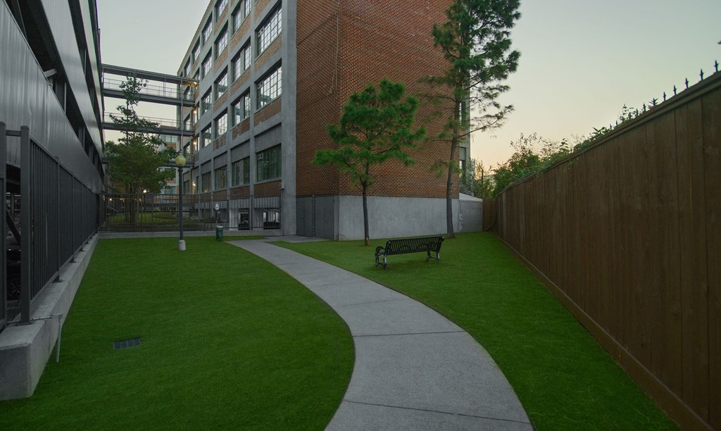 A green lawn with a concrete walkway and a bench.