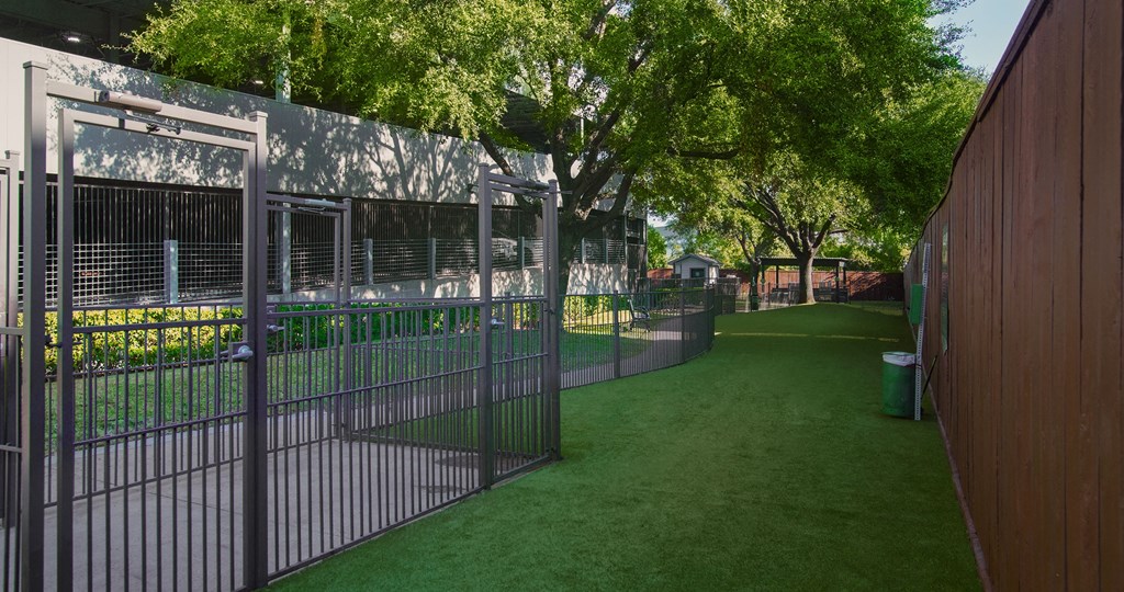 A metal fence surrounds a green field.
