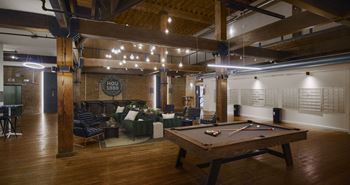 A pool table is in the middle of a room with a couch and chairs.