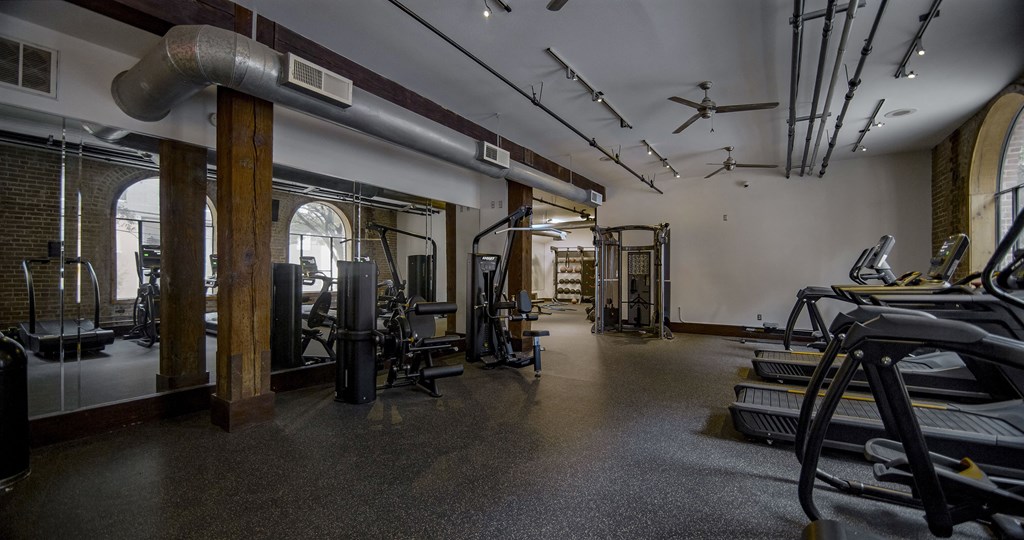 A gym with a variety of equipment including treadmills, weights, and exercise machines.