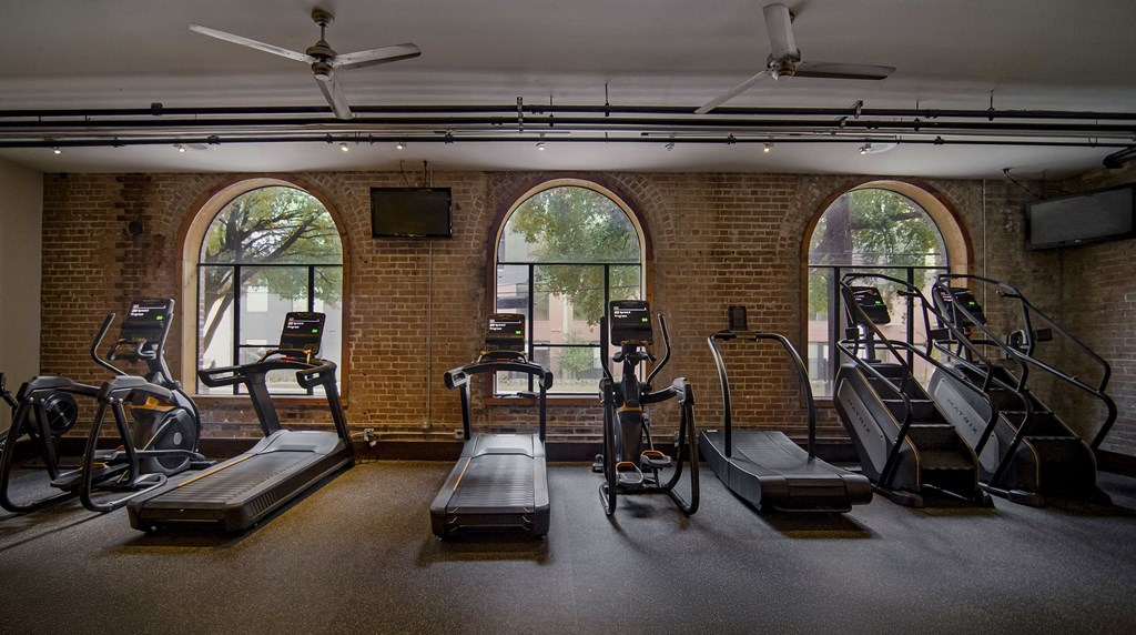 A gym with treadmills, elliptical machines, and a television.