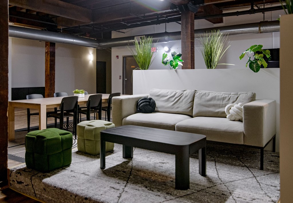 A living room with a white couch and a green ottoman.