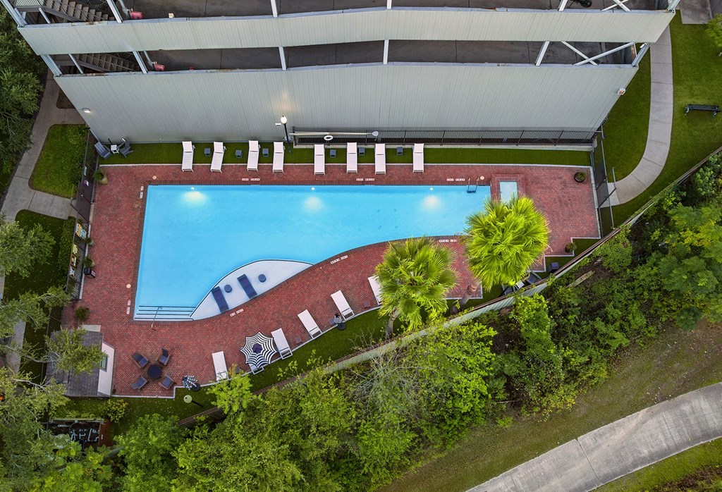An aerial view of a swimming pool surrounded by trees and a building.