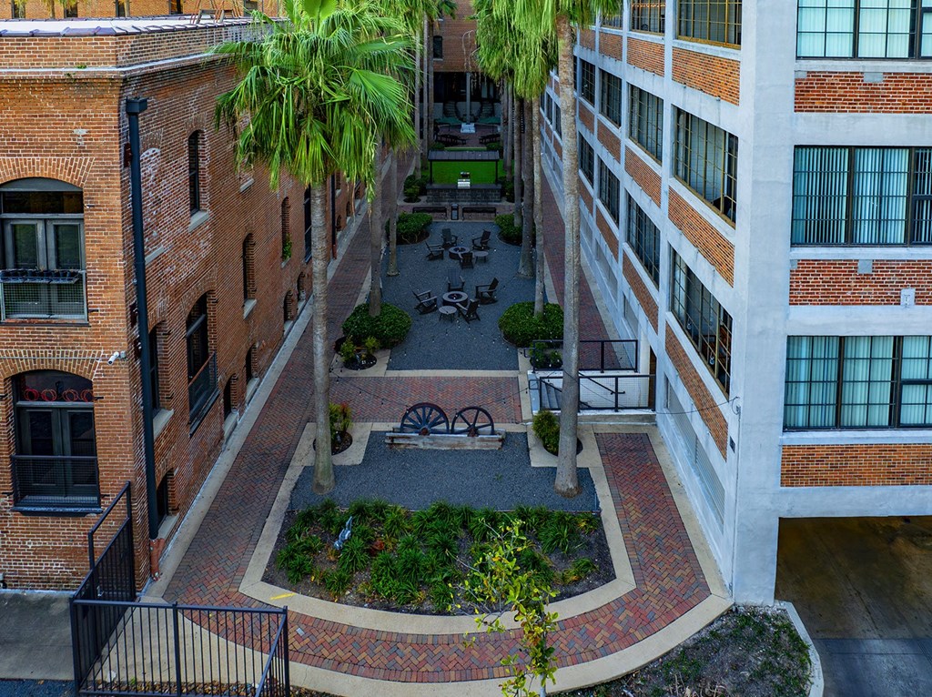 A courtyard surrounded by brick buildings with a fence and a tree.
