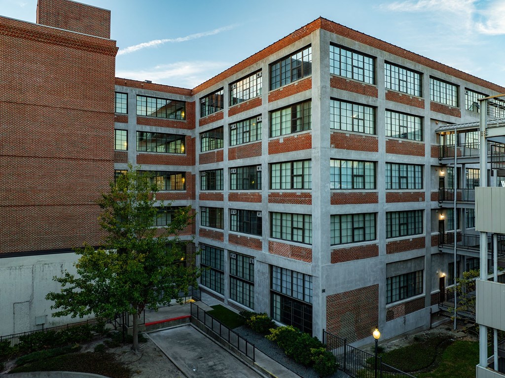 A large red brick building with many windows and a tree in front.
