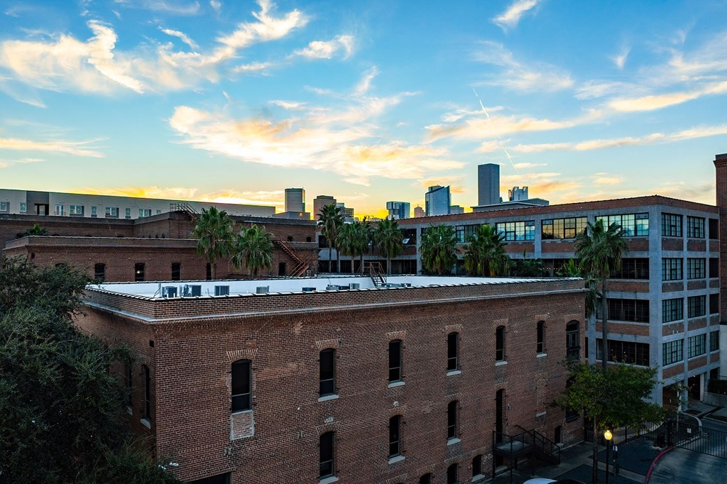 A red brick building with a white roof is in the foreground with a city skyline in the background.