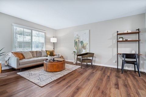 A living room with a white couch, a wooden coffee table, and a painting on the wall.