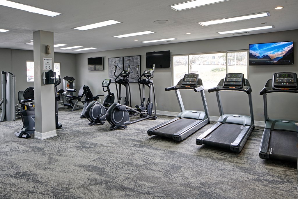 a gym with cardio equipment and televisions in a building