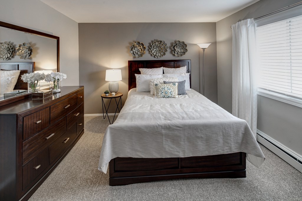 a bedroom with a bed and a dresser and a window