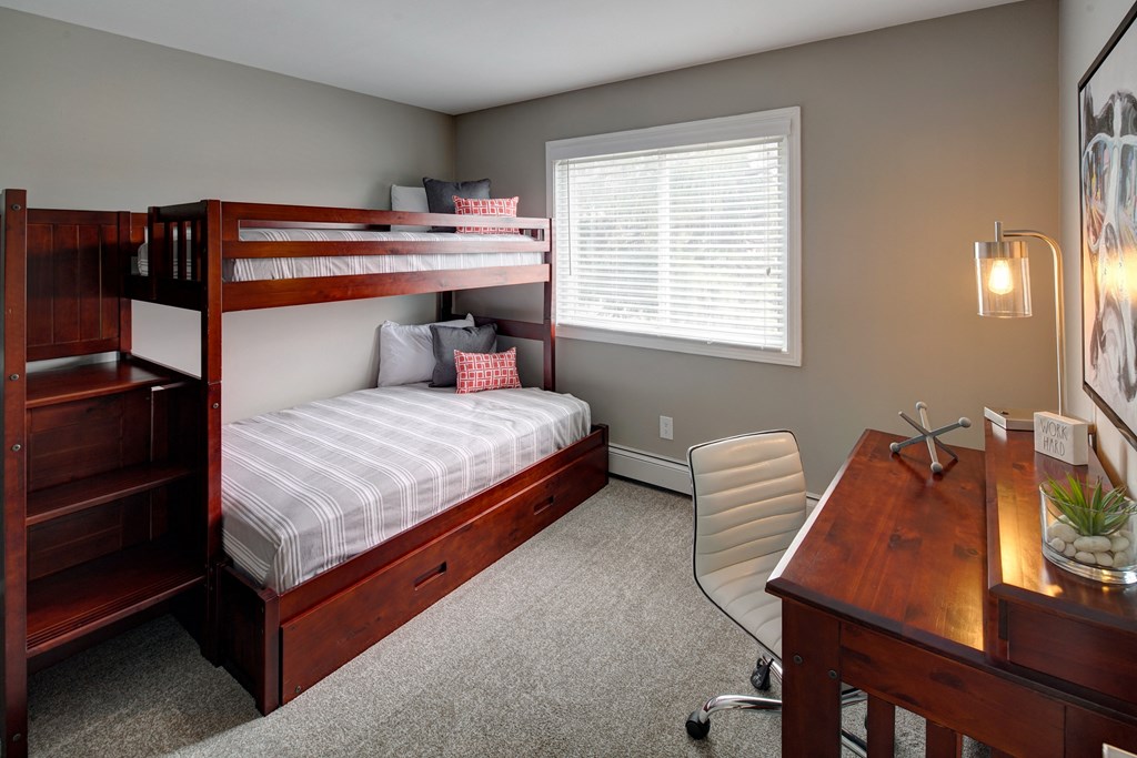 a bunk bed in a room with a desk and a chair