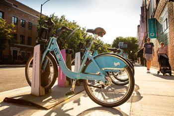 A blue bicycle with the word "LYFT" on the front wheel is parked on a sidewalk.