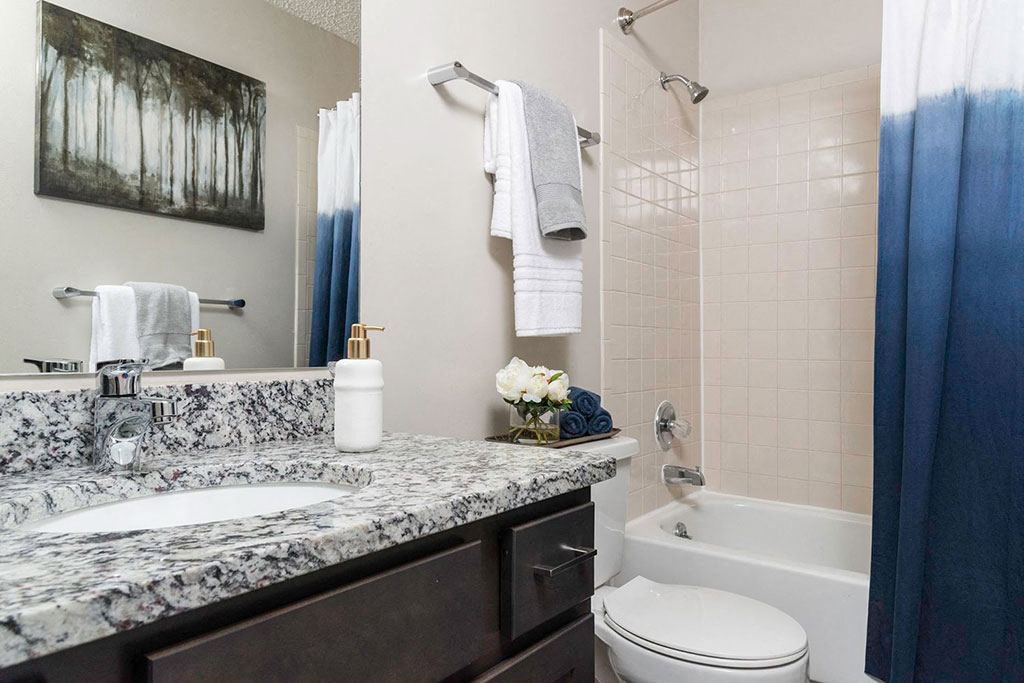 bathroom with a granite-countertop vanity and white tub