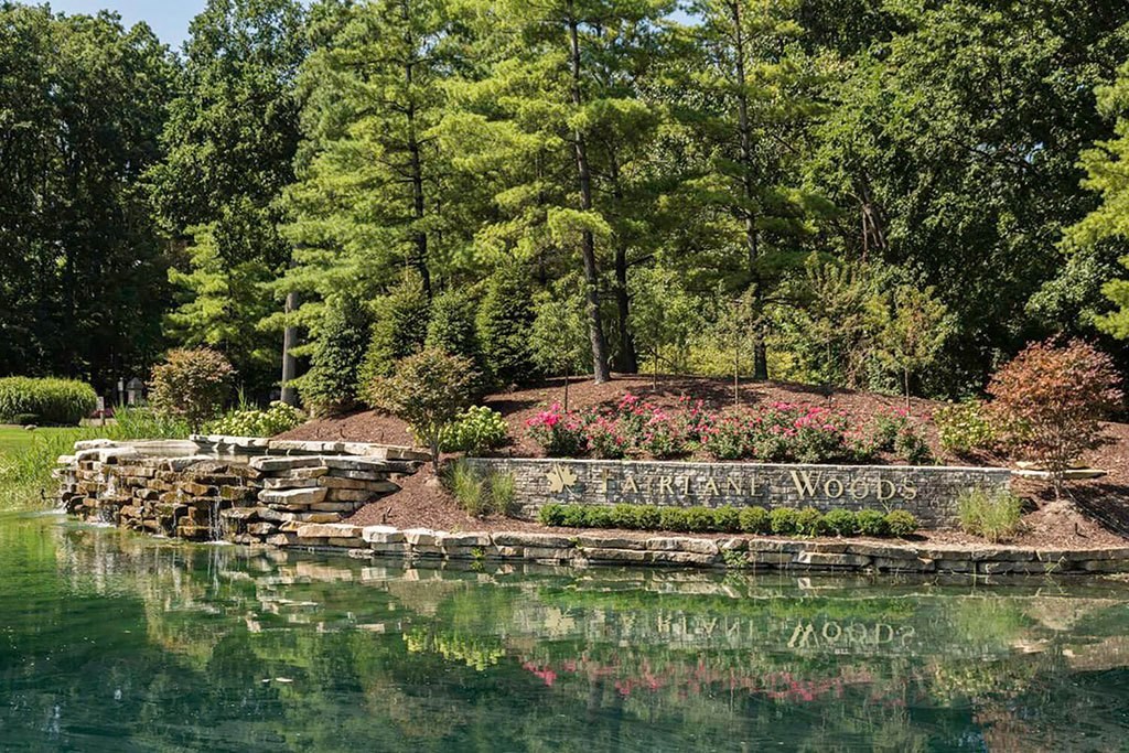Fairlane Woods sign surrounded by lush landscaping and a lake