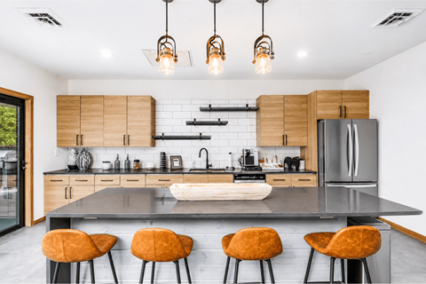 A modern kitchen with a large island and four orange chairs.