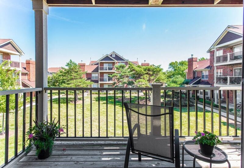 a balcony with a chair and a view of a yard