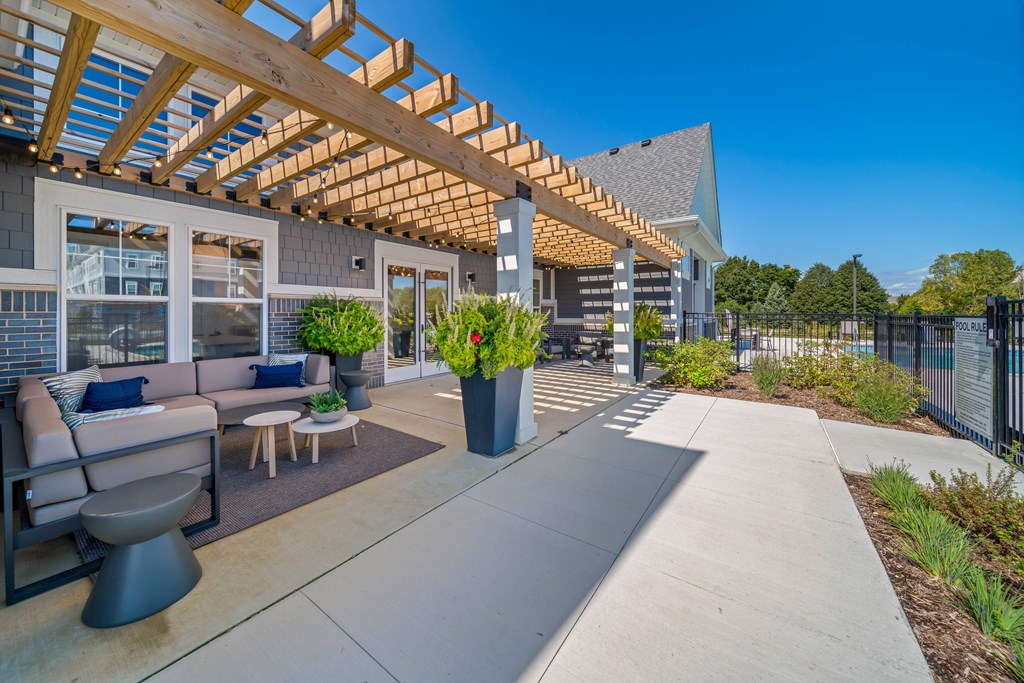 A modern outdoor seating area with a wooden pergola and a concrete floor.