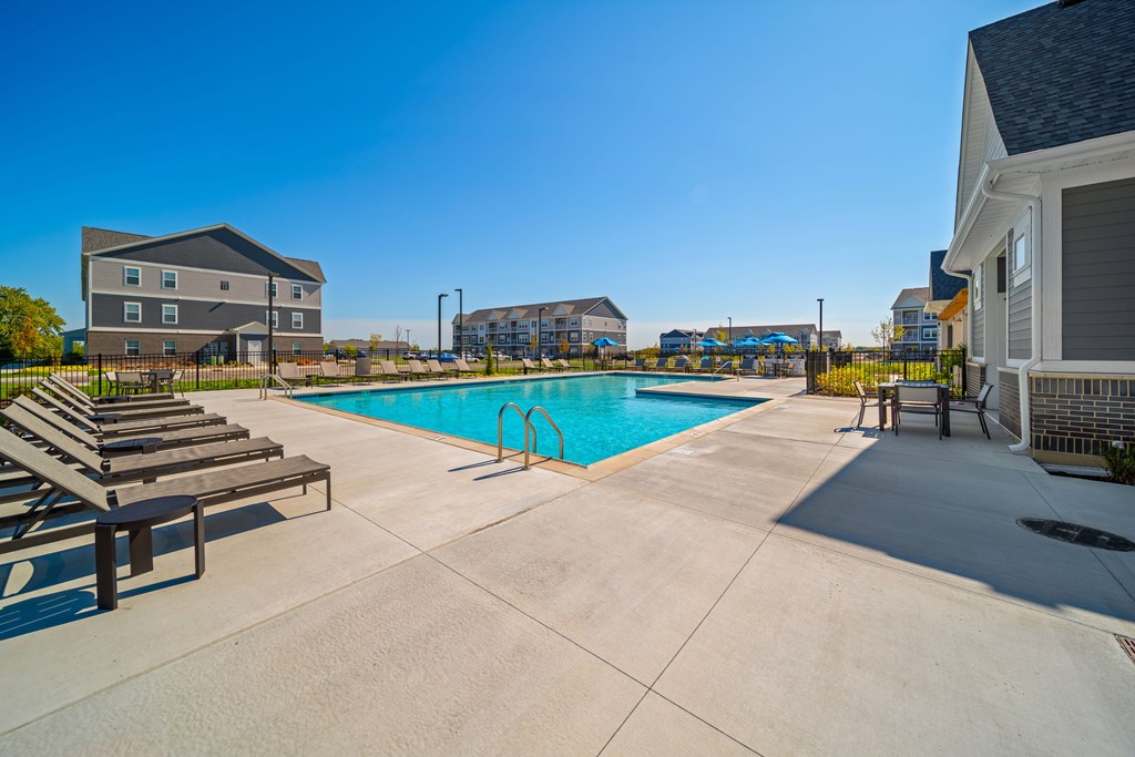 A swimming pool with sun loungers and a building in the background.
