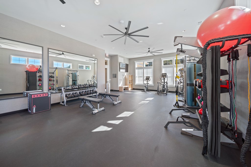 A gym with a variety of equipment including a red exercise ball.