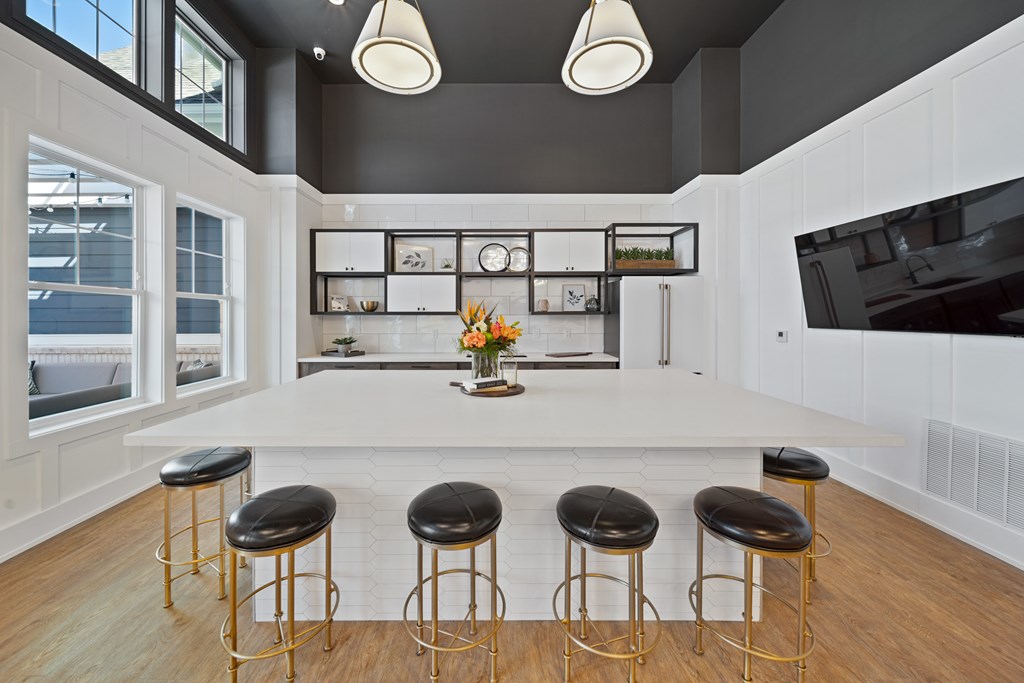 A kitchen with a white counter and black stools.