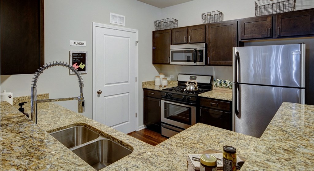 stainless appliances and marble counter tops at Algonquin Square Apartment Homes, Algonquin, IL, 60102 spacious kitchen with granite countertops, dark wood cabinets, and stainless steel appliances