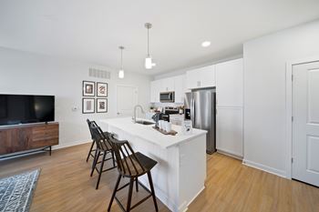A kitchen with a white island and wooden chairs.