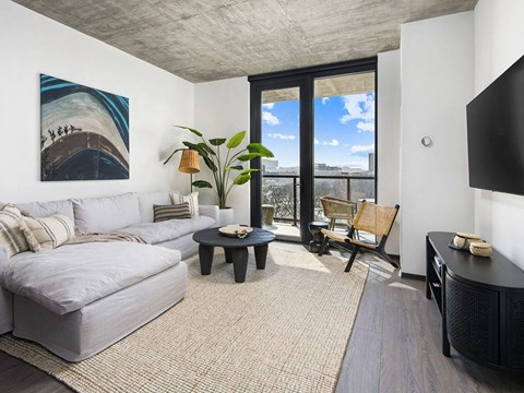 A living room with a grey couch, a black coffee table, and a painting on the wall.
