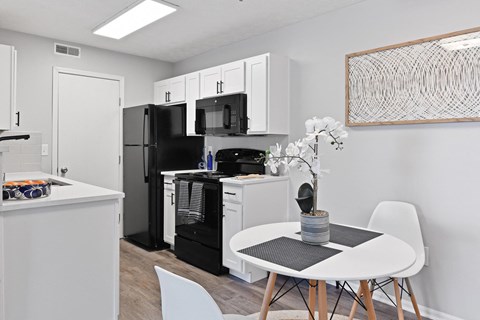 a white kitchen with black appliances and a table and chairs