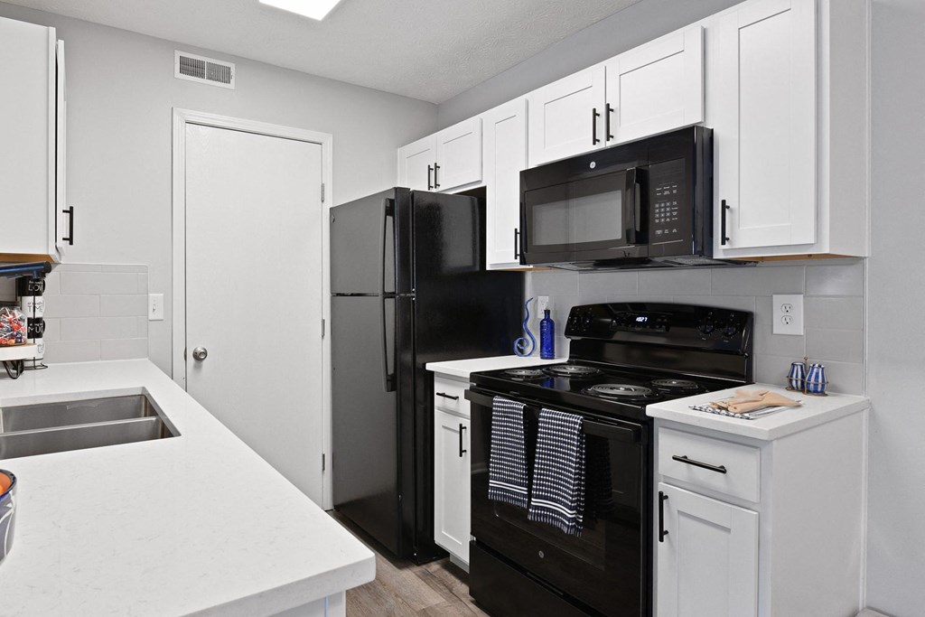 an empty kitchen with black appliances and white cabinets