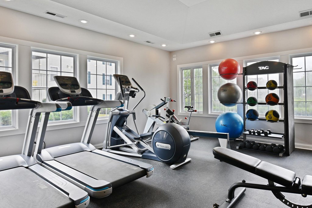a gym with treadmills and other exercise equipment and windows