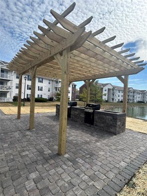 a picnic area with a wooden pavilion and a grill