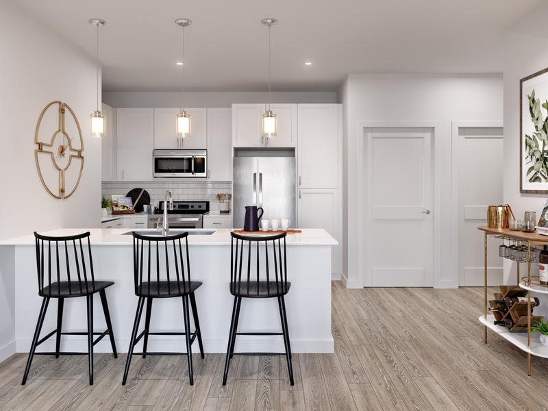 A kitchen with white cabinets and a wooden floor.