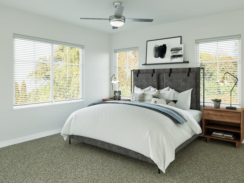 A bedroom with a large bed and a ceiling fan.