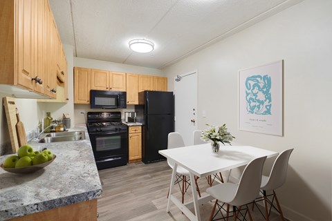 A kitchen with a table and chairs in front of it.