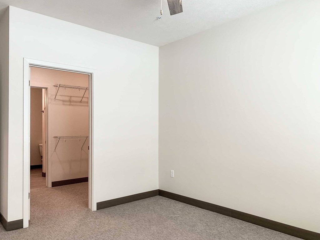 a bedroom with a walk-through closet to a  bathroom