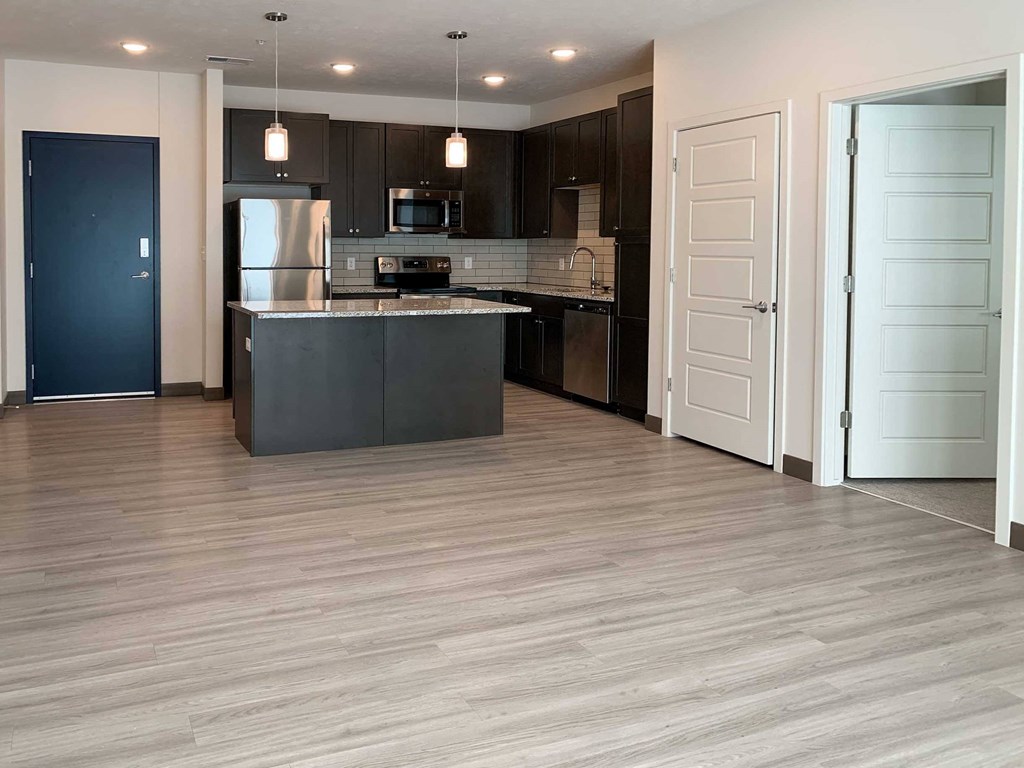 a living room and kitchen with dark cabinets and light granite
