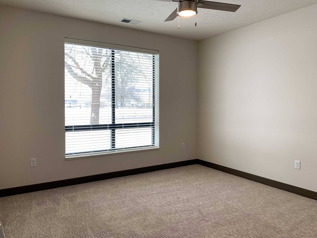 a bedroom with a large window and a ceiling fan