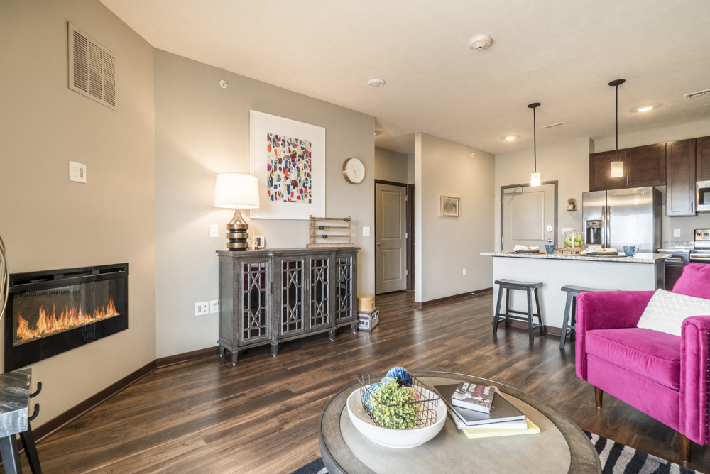 One bedroom apartment living room with modern fireplace and hardwood-style floors at 360 at Jordan West best new apartments West Des Moines IA 50266