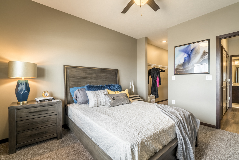Bedroom with ceiling fan, walk-in closet and master bath at 360 at Jordan West best new apartments West Des Moines IA 50266