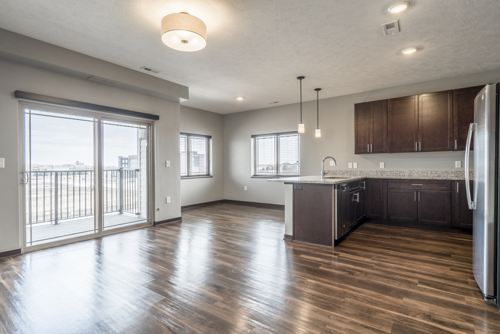 View from living room of kitchen and dining room with hardwood-style floors and balcony at 360 at Jordan West best new apartments West Des Moines IA 50266