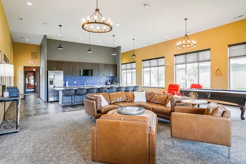 A living room with a brown leather couch and a grey carpet.