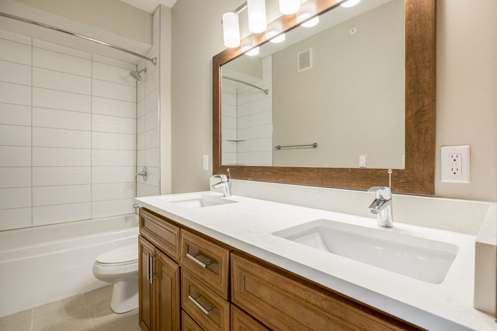 Dual sinks in bathroom with tiled tub in premium unit at Ascend at Woodbury new luxury apartments in Woodbury MN 55129
