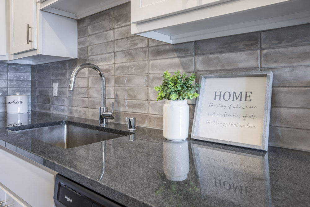 Designer Grohe-brand faucets, granite countertops and kitchen backsplash at Ascend at Woodbury MN 55129 new luxury apartments